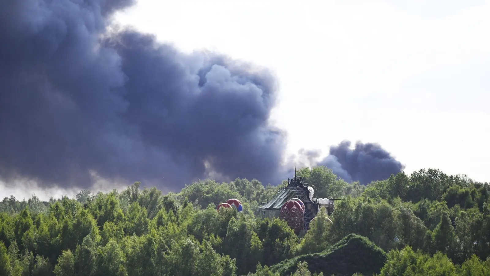 Vom Gelände des Tomorrowland-Festivals steigt am Mittwoch dunkler Rauch auf: Die Größe der Rauchwolke lässt das Ausmaß des Brandes erahnen. (Bild: Tom Goyvaerts/Belga/dpa)